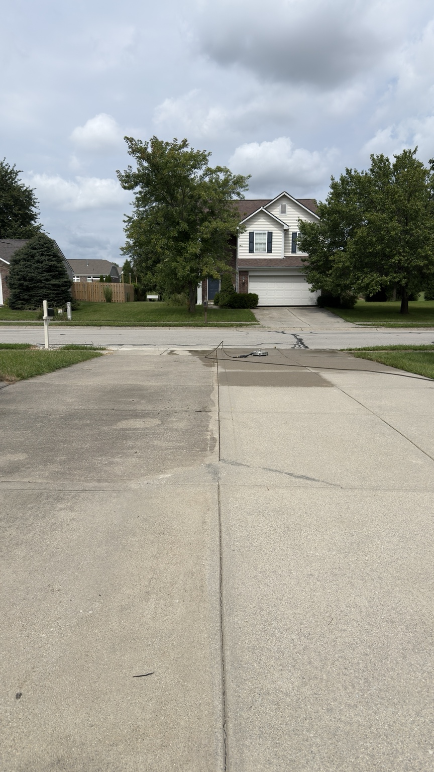 Driveway pressure washing progress showing clean and dirty concrete