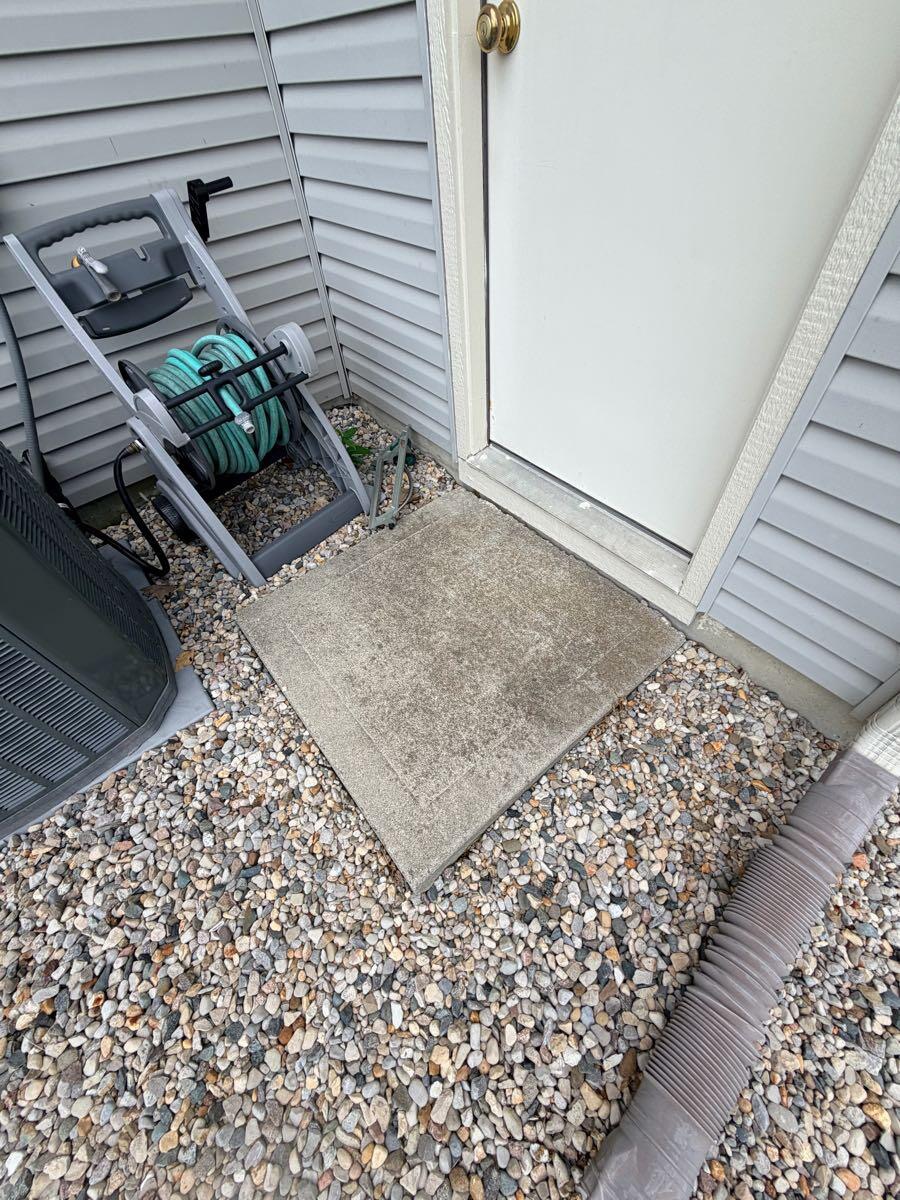 Small concrete pad by side door before pressure washing
